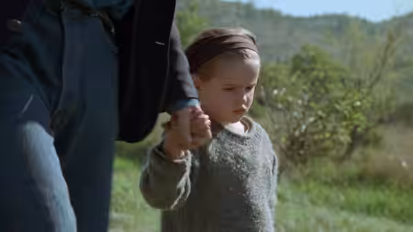 Ponette (Victoire Thivisol) walks outdoors holding an adult's hand