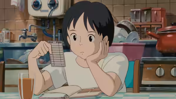 Boy holds up a card while seated at kitchen table with book