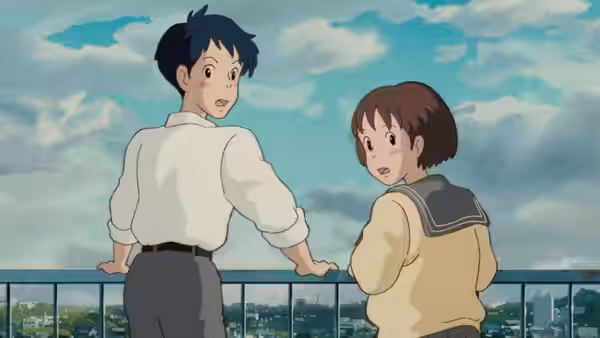 Boy and girl stand together on balcony overlooking cityscape under blue sky