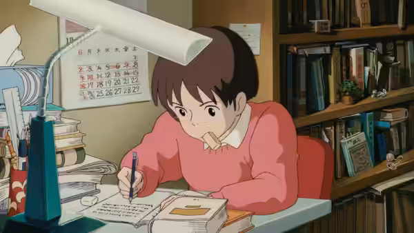 Girl in pink sweater writes in notebook at desk piled with books