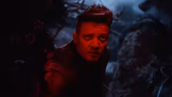 Clint Barton (Jeremy Renner) crouches alert in a dark rocky outdoor setting