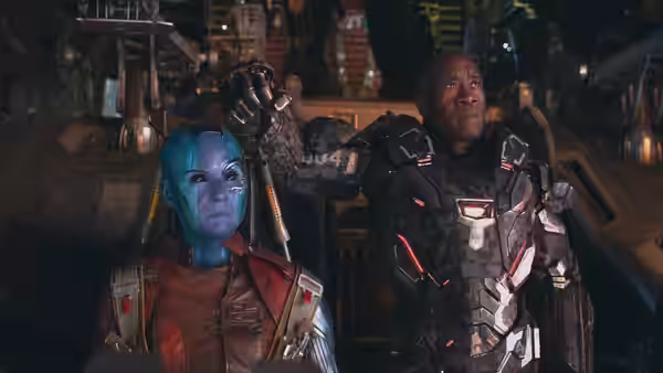 Nebula and War Machine (Don Cheadle) stand side by side in a dim alien hangar