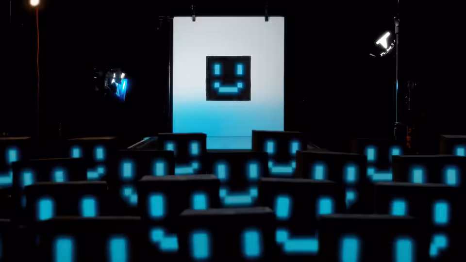 A dark auditorium with rows of glowing blue pixel smiley faces facing a large screen