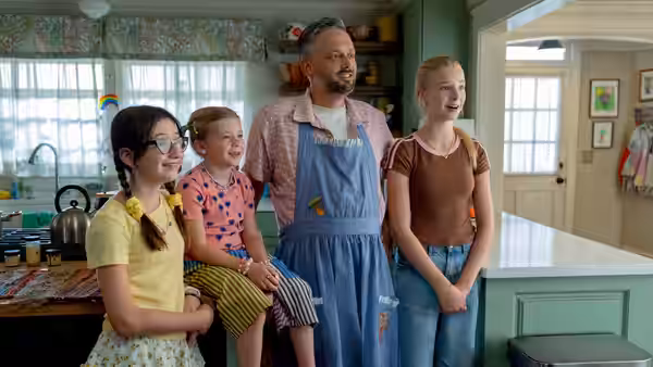 Nate Wilcox (Nate Bargatze) in apron standing with three young girls in kitchen