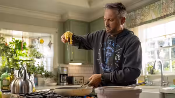 Nate Wilcox (Nate Bargatze) lifting spaghetti from pan on stove in kitchen