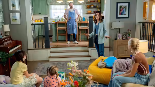 Nate Wilcox (Nate Bargatze) in apron standing on stairs while Katie Wilcox (Mandy Moore) gestures