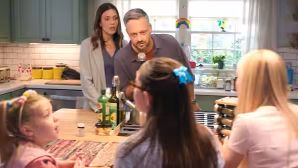 Nate Wilcox (Nate Bargatze) and Katie Wilcox (Mandy Moore) standing over children at kitchen table