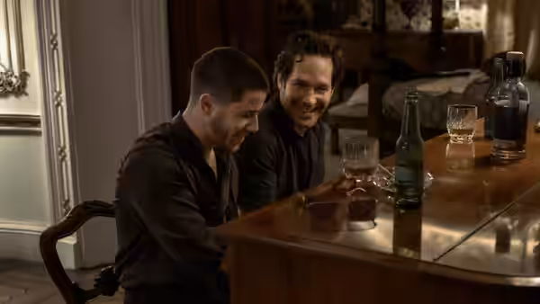 Danny Wilson (Nick Jonas) and Rick (Paul Rudd) smiling over drinks at a table