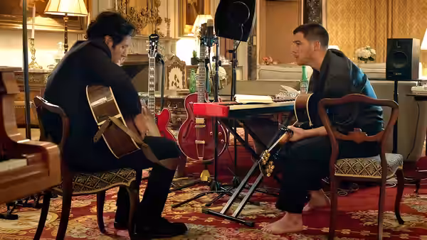 Danny Wilson (Nick Jonas) playing guitar across from another musician in a studio