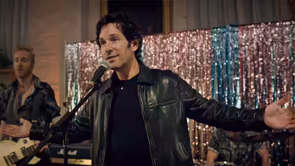 Rick (Paul Rudd) singing into a microphone with arms outstretched on stage