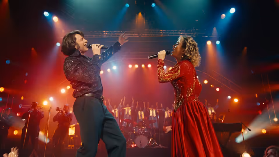 Mike Sardina (Hugh Jackman) and Claire Sardina (Kate Hudson) singing together on a concert stage