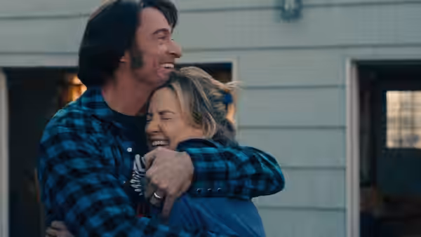 Mike Sardina (Hugh Jackman) and Claire Sardina (Kate Hudson) embracing and smiling outdoors