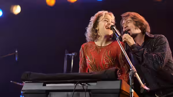 Mike Sardina (Hugh Jackman) and Claire Sardina (Kate Hudson) singing at a microphone on stage