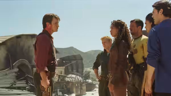 Mal Reynolds (Nathan Fillion) facing Zoë Washburne (Gina Torres) and crew outside