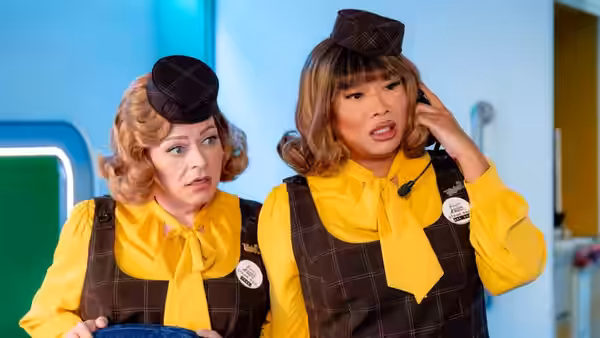 Two flight attendants in yellow shirts and vests react with concern
