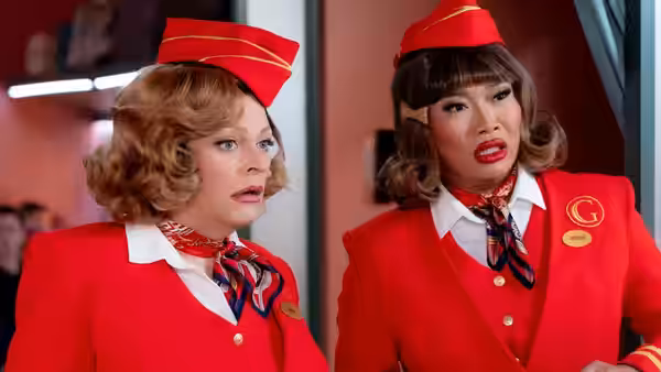 Two flight attendants in red uniforms look aside with surprised expressions