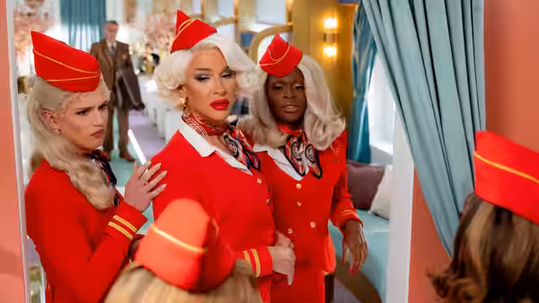 Three flight attendants in red uniforms stand together in a colorful lounge