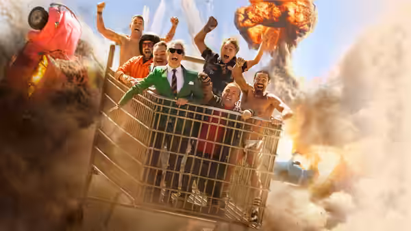 Group of men cheer from a large metal cart amid fiery explosions