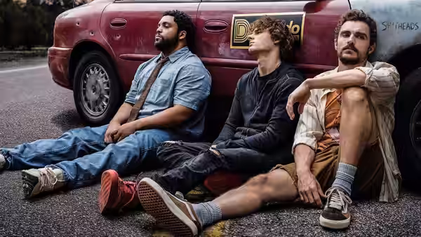 Davis Sheridan and Mark sitting on the road against a red car