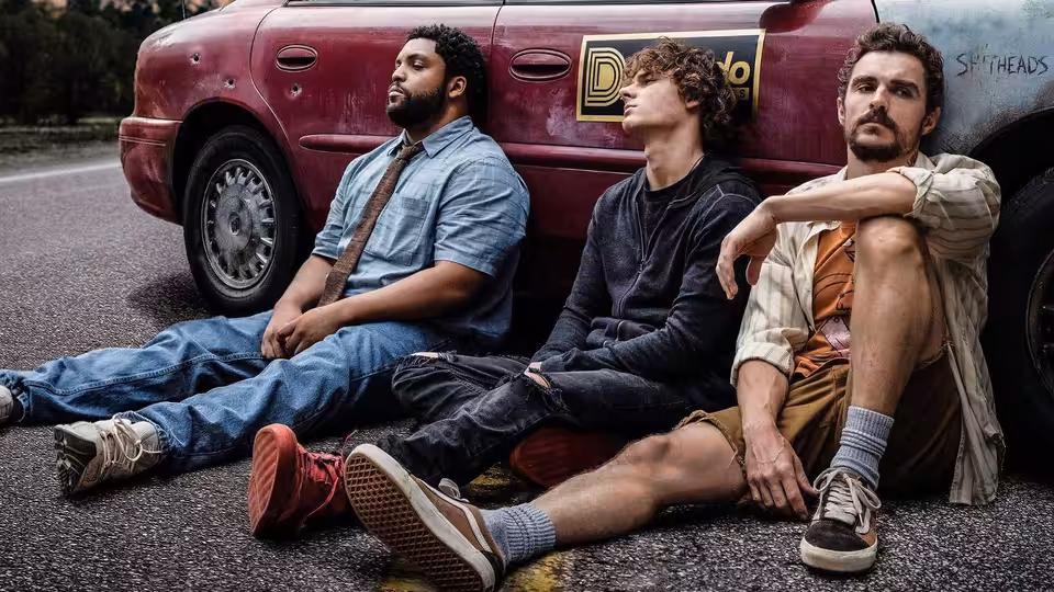 Davis Sheridan and Mark sitting on the road against a red car