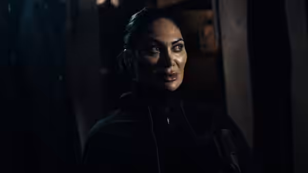 Ros Knight (Jeanine Nerissa Sothcott) looking ahead in a dim interior