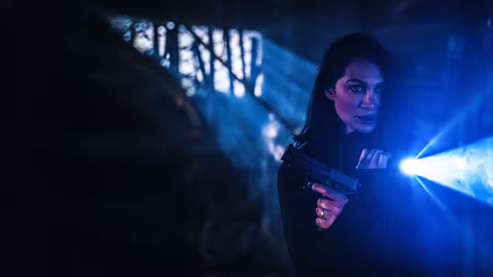 Ros Knight (Jeanine Nerissa Sothcott) aiming a pistol with flashlight in darkness