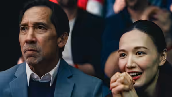 Asian man and woman seated in an audience watching with hands clasped