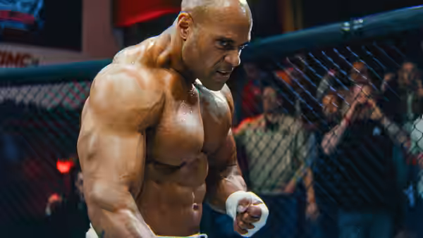 Bald muscular fighter standing sweaty inside an octagon cage