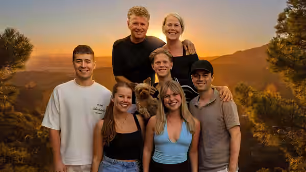 Self (Wolter Kroes) poses with family members and a small dog against a sunset-lit valley