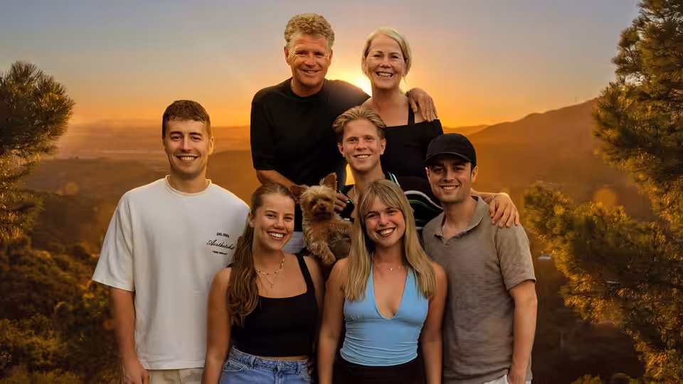 Self (Wolter Kroes) poses with family members and a small dog against a sunset-lit valley