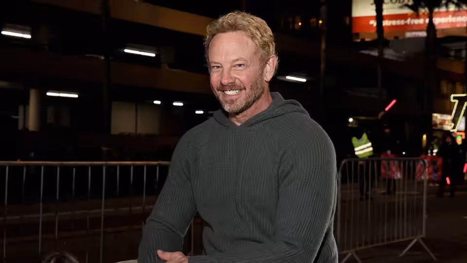 Host Ian Ziering smiles beside a railing at a nighttime event