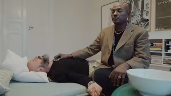 Durek Verrett rests hand on Magnus Støre lying on a couch