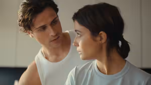 A young man and woman look at each other indoors