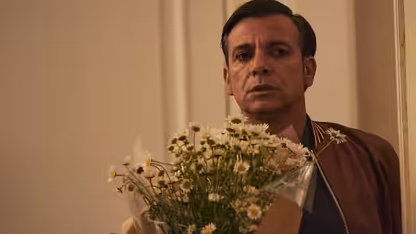 Man holding large bouquet of white daisies standing in hallway