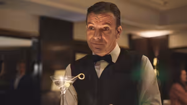 Man in bow tie and vest holding martini glass with olive