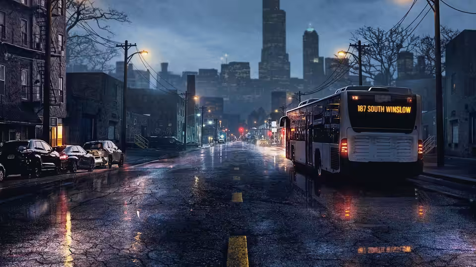 A city bus driving on a wet street at night toward distant skyscrapers