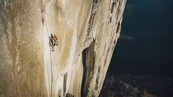 A climber ascending a massive rock wall on ropes