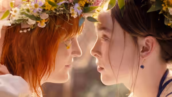 Two young women in flower crowns lean close face to face