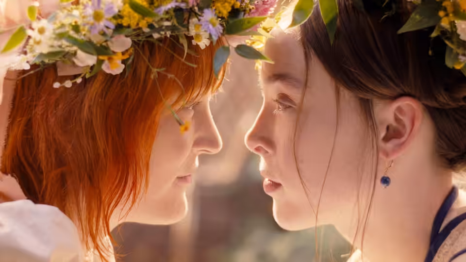 Two young women in flower crowns lean close face to face