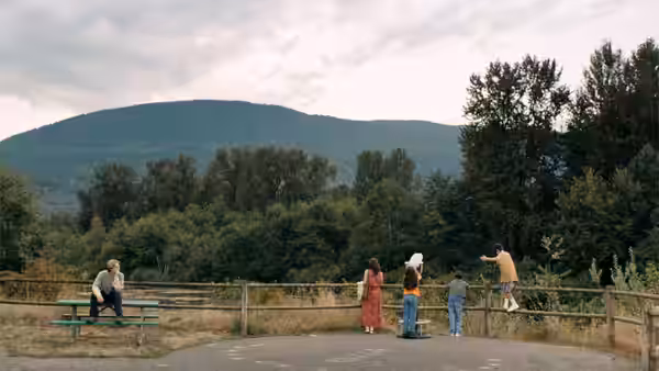 A group of people standing by a wooden fence overlooking a mountain