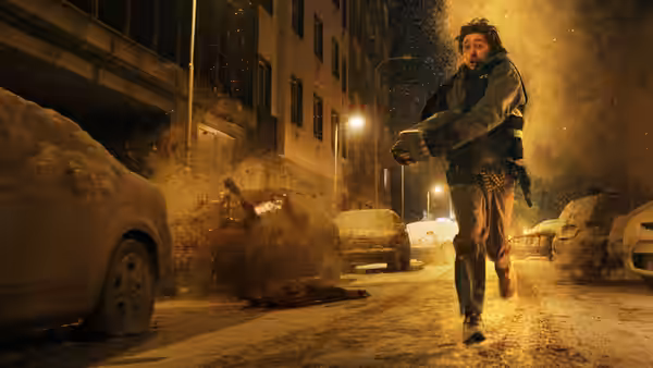 Man runs through snowy street past burning car and body on the ground