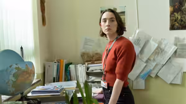 Maria (Saoirse Ronan) standing in a cluttered staffroom