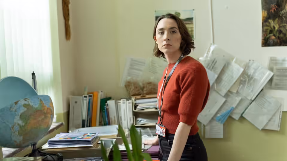 Maria (Saoirse Ronan) standing in a cluttered staffroom