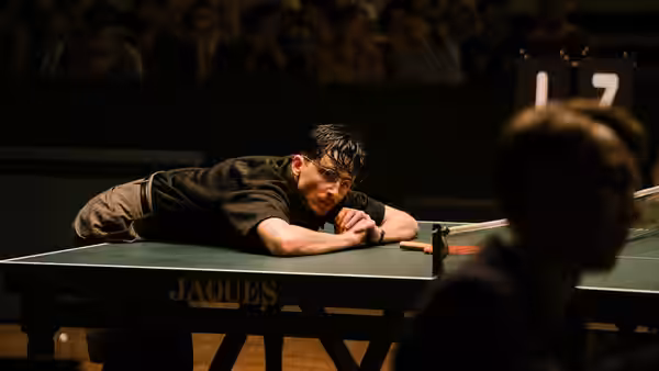 Marty Mauser (Timothée Chalamet) leaning on a table tennis table