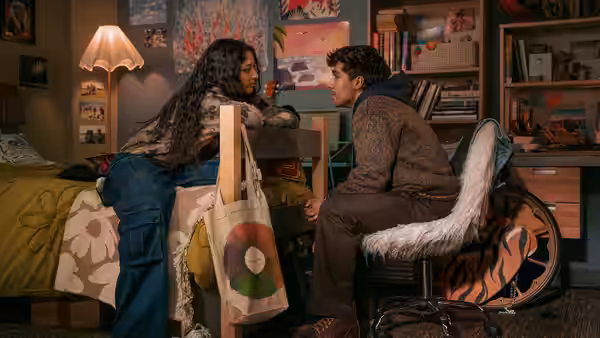 woman leaning forward speaking to a seated man in a dorm room