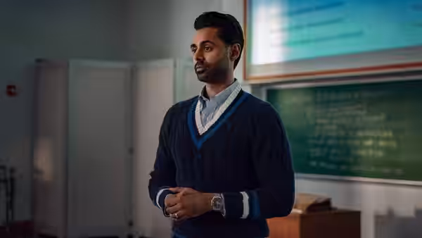man in a blue sweater vest standing with hands clasped in class