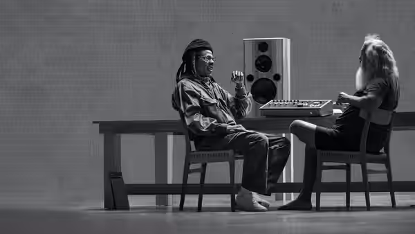 JAŸ-Z gesturing while seated across from Rick Rubin at a mixing console