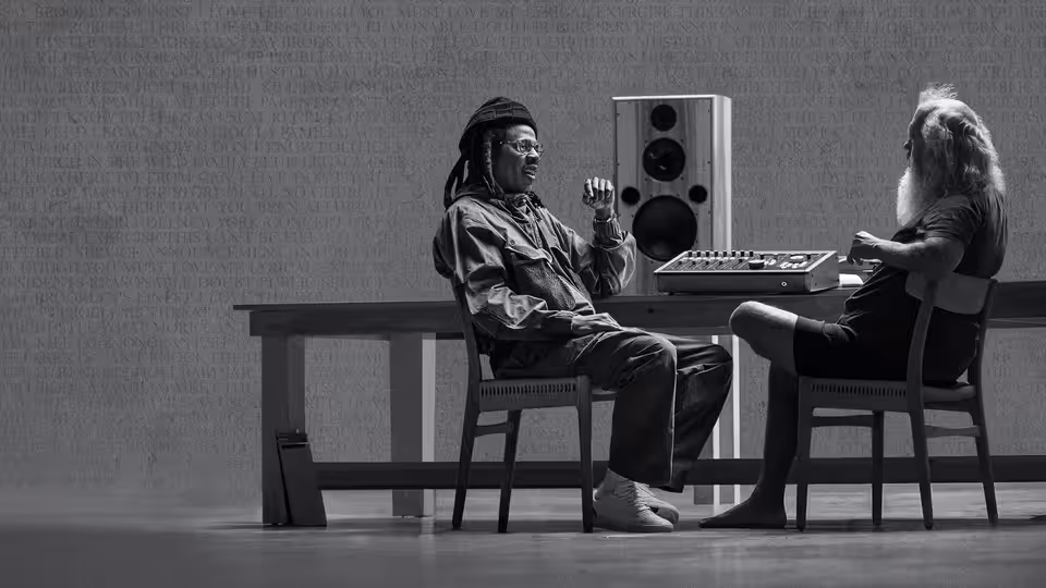 JAŸ-Z gesturing while seated across from Rick Rubin at a mixing console