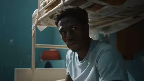 A man sitting on a bunk bed inside a prison cell