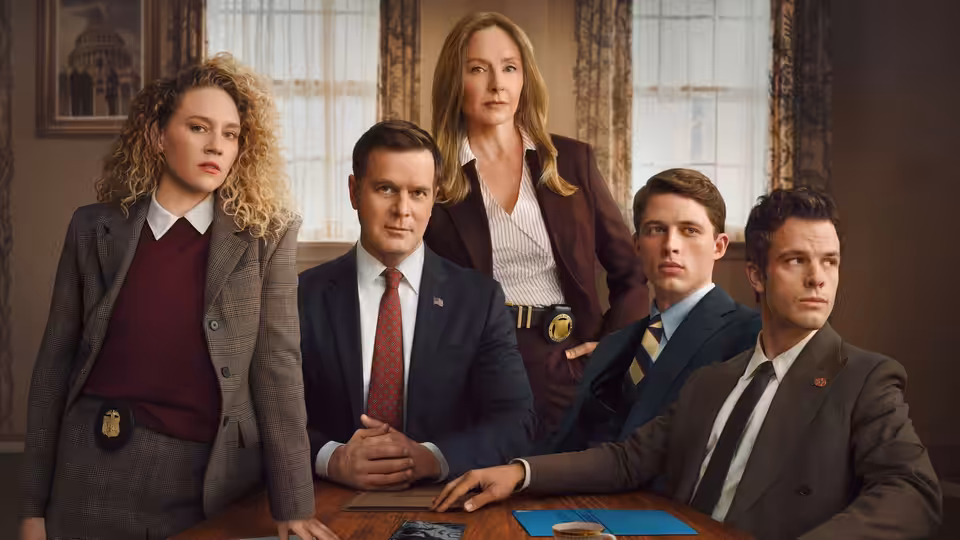 Five professionals in suits gathered around a wooden table in an office